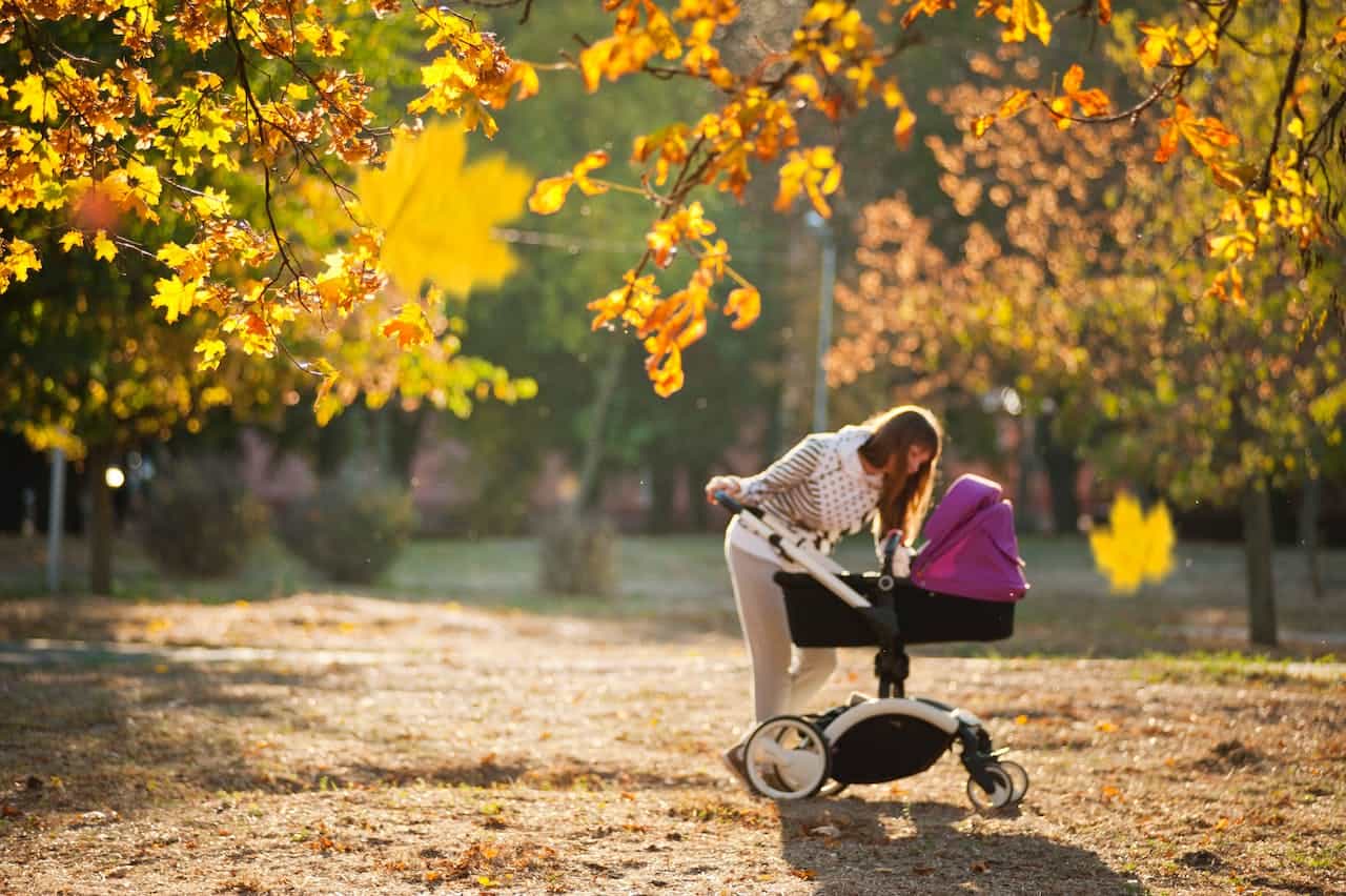 Mamma med barnvagn i solen